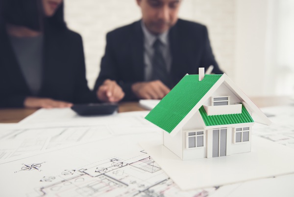 Ein Mann und eine Frau sitzen an einem Tisch und beraten über Wohneigentum erwerben